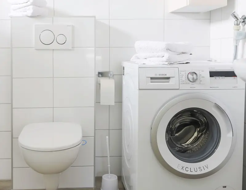 The washing machine stands in the bathroom of cottage&nbsp;2, beside the toilet.