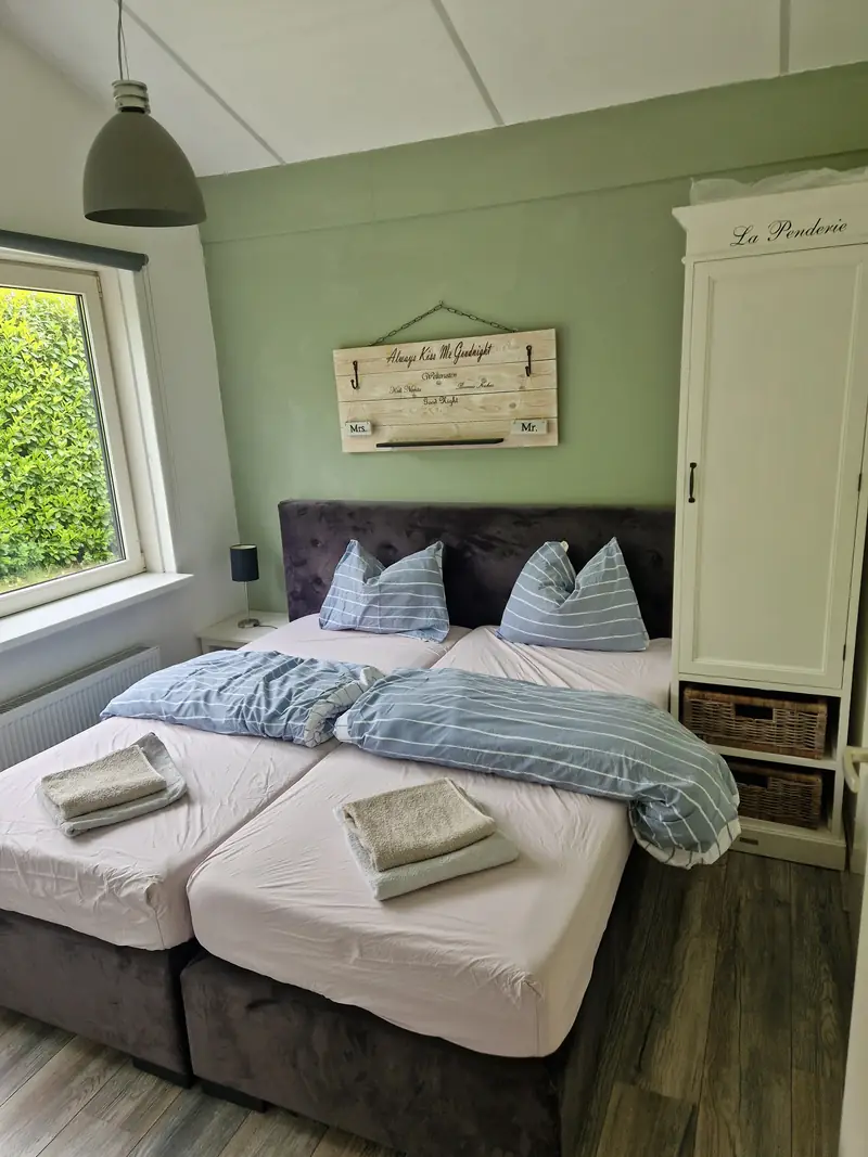 De grote slaapkamer van huisje&nbsp;2, met het tweepersoonsbed en een witte kledingkast.
