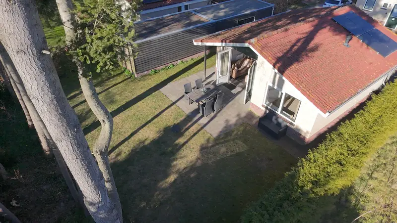 De achterkant van huisje&nbsp;3 met het terras en de tuin, van bovenaf gezien.