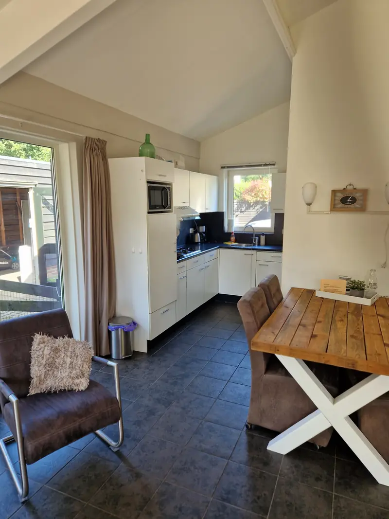 Die Küche von Haus&nbsp;3 mit Gaskochfeld, Dunstabzug, Mikrowelle und einem kleinen Tisch.