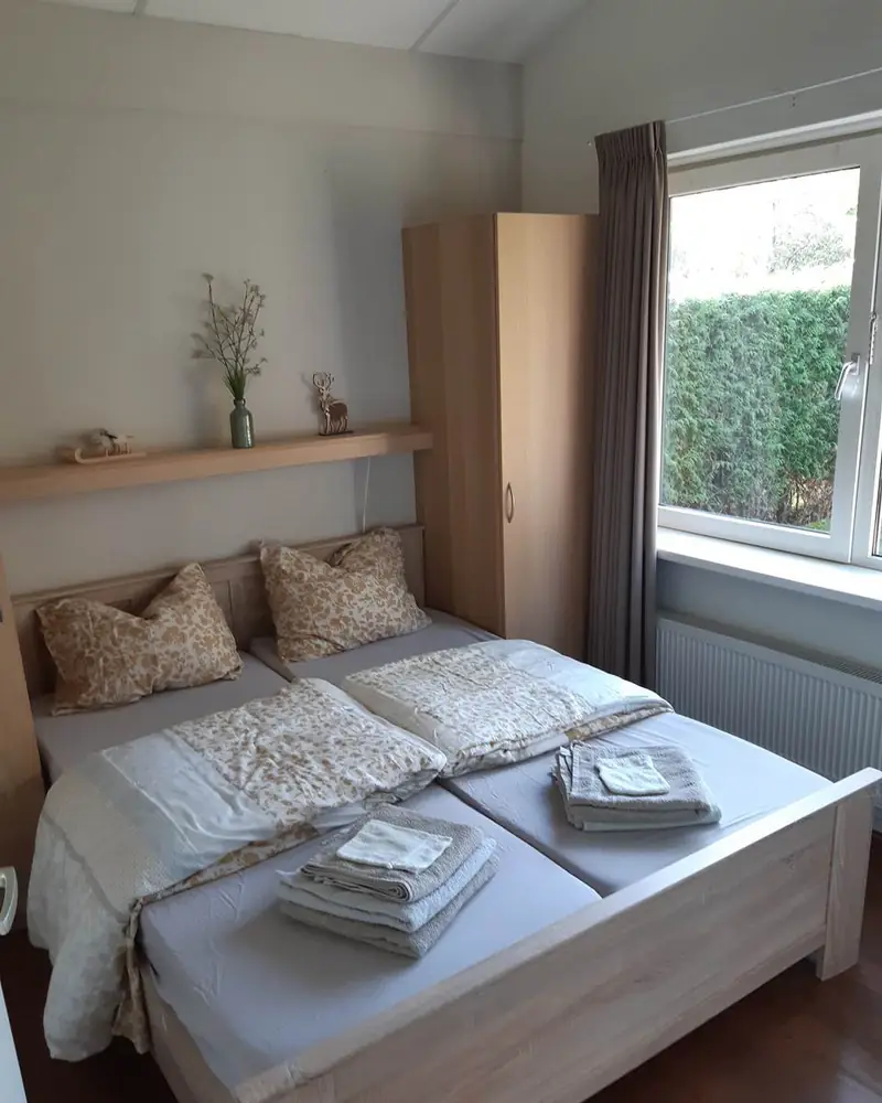 Das erste Schlafzimmer von Haus&nbsp;3 mit dem Doppelbett und dem Fenster zur Hecke.