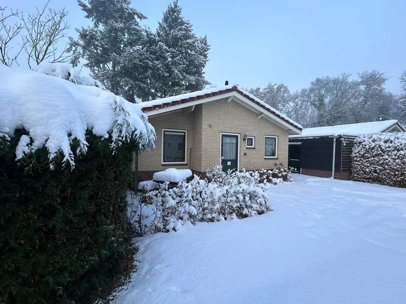 Die Vorderseite von Haus 3 im Winter, mit Schnee auf der Zufahrt und der Hecke.
