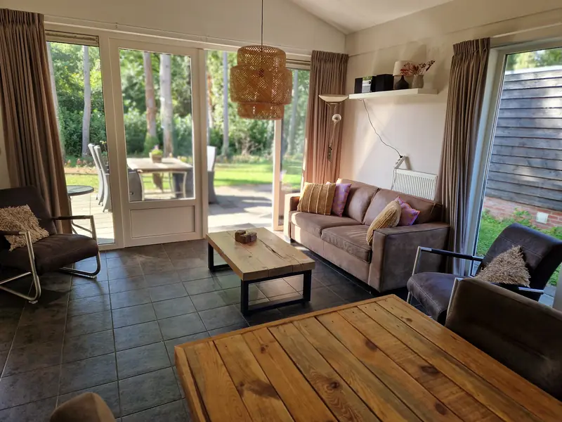 De woonkamer van huisje&nbsp;3, met de terrasdeuren open naar de tuin.
